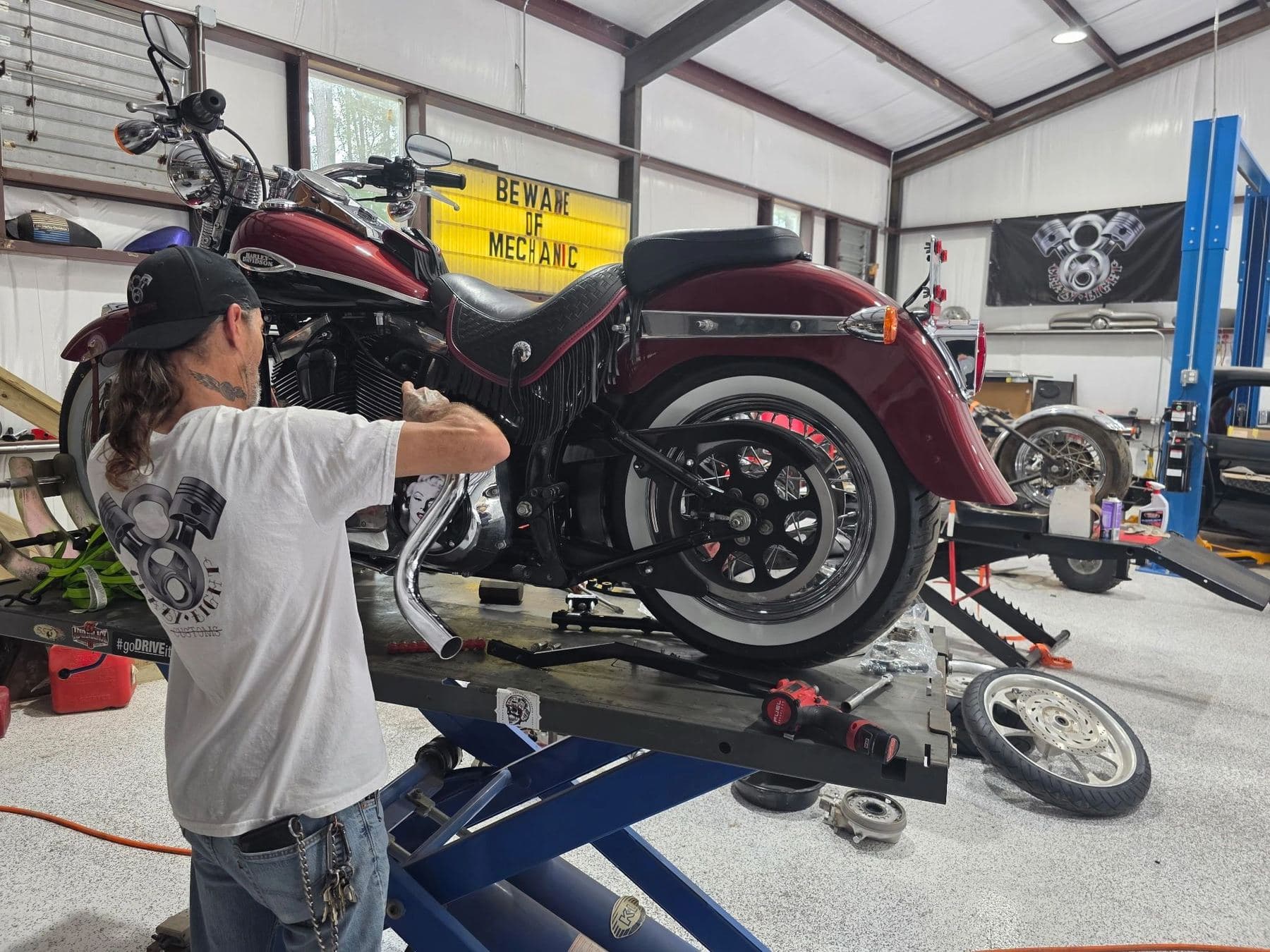 Mechanic working on a Harley on a lift in the Crazy Eight Customs bay